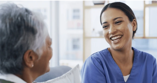 Profissional de enfermagem sorrindo para a paciente idosa