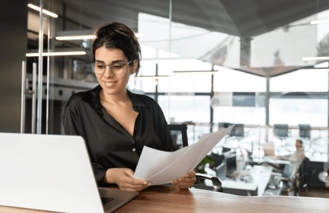 Gestora financeira conferindo comprovantes ao notebook