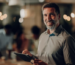 Dono de empresa de home care sorrindo, com o tablet na mão, em meio à equipe