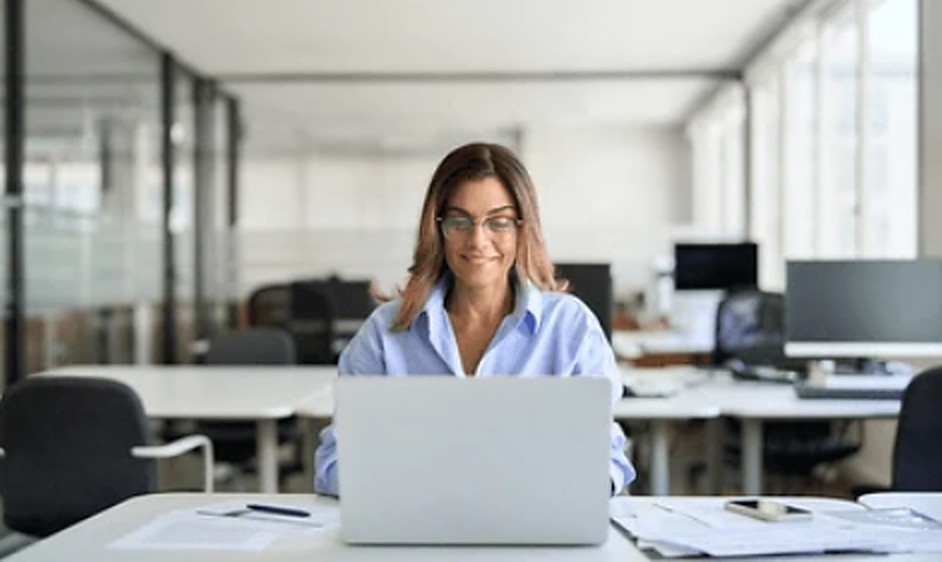 Escalista sorrindo diante do notebook, no escritório da empresa