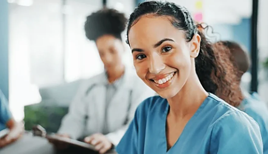 Profissional de enfermagem sorridente em reunião com a equipe